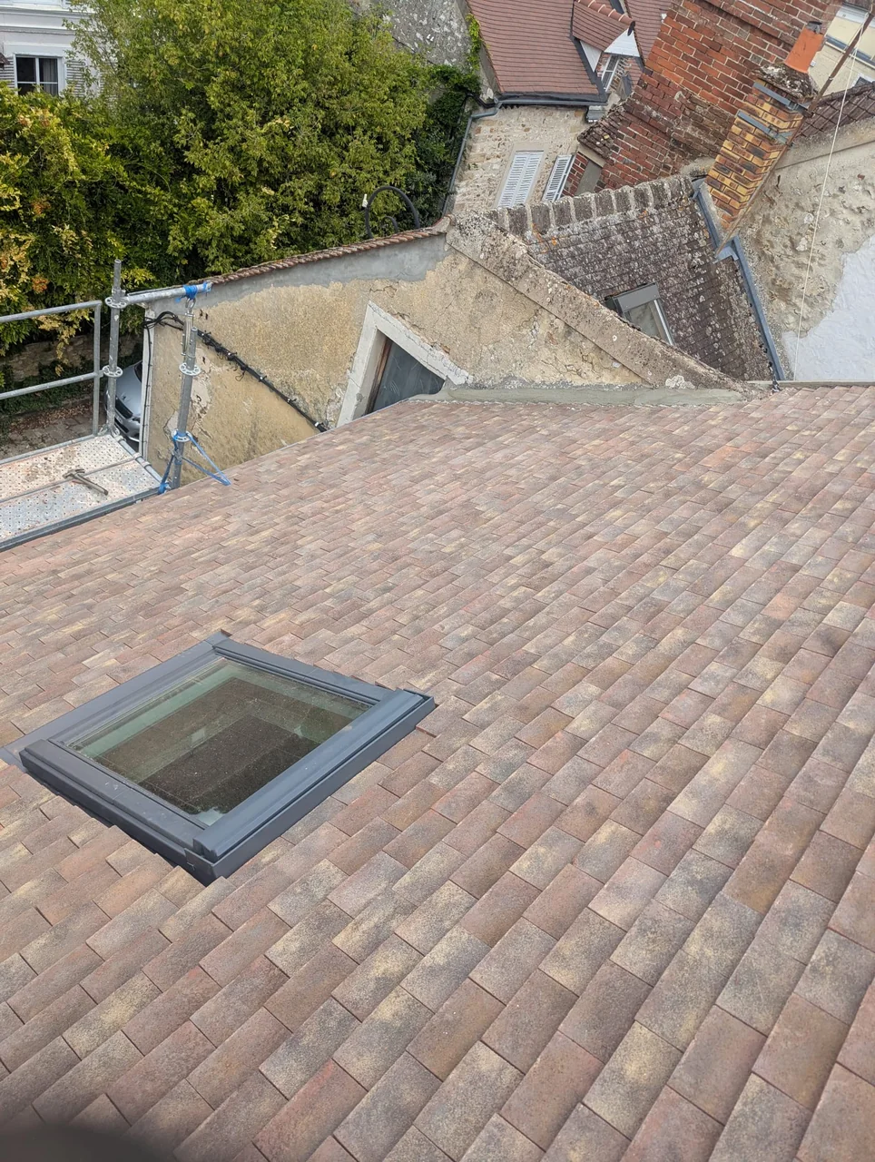 Vue d’une couverture en tuiles avec une fenêtre de toit à Compiègne